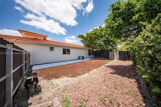 rear view of property with fence, stucco siding, a patio area, a tiled roof, and a storage shed