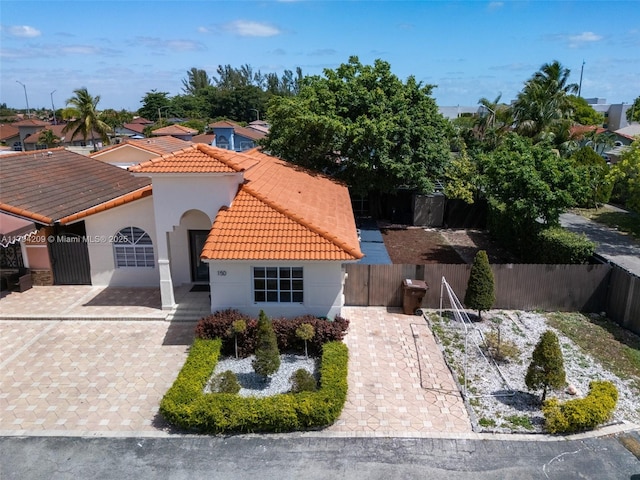 view of front of home with decorative driveway, fence, a tile roof, and stucco siding