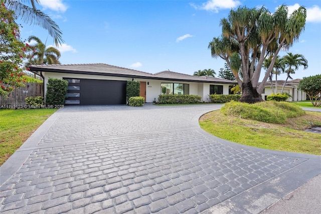 single story home with fence, curved driveway, a front lawn, and a garage