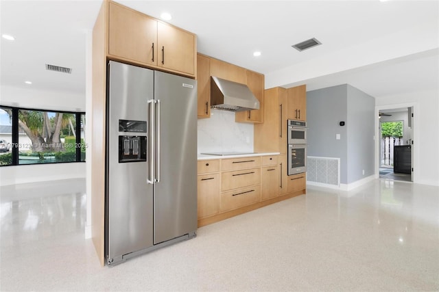 kitchen with appliances with stainless steel finishes, a wealth of natural light, wall chimney exhaust hood, and visible vents