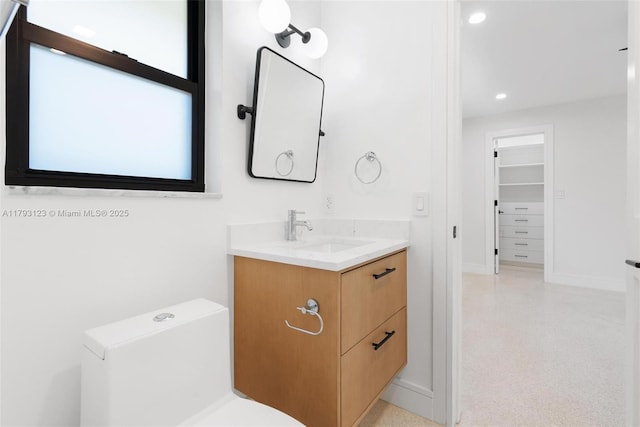 bathroom featuring vanity, baseboards, and recessed lighting