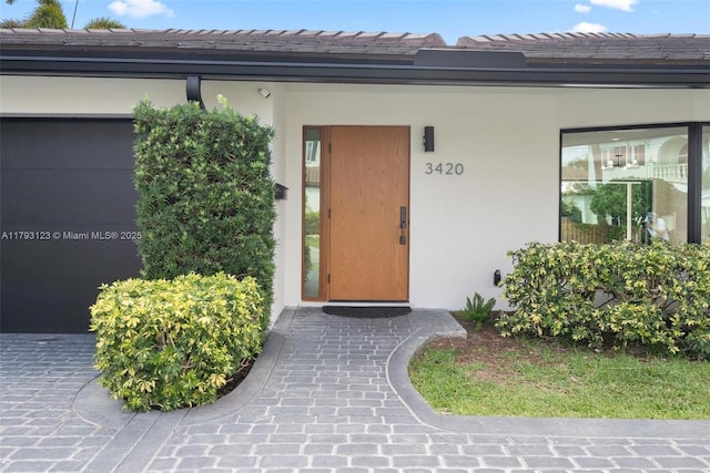 property entrance featuring a tile roof and stucco siding
