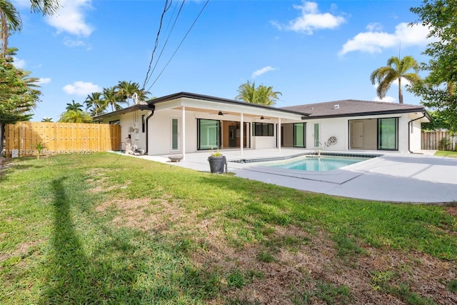 rear view of property featuring a ceiling fan, a patio, stucco siding, and a yard