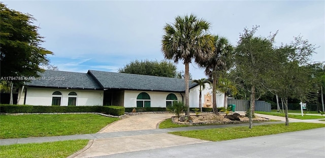 single story home with decorative driveway, a front lawn, and stucco siding