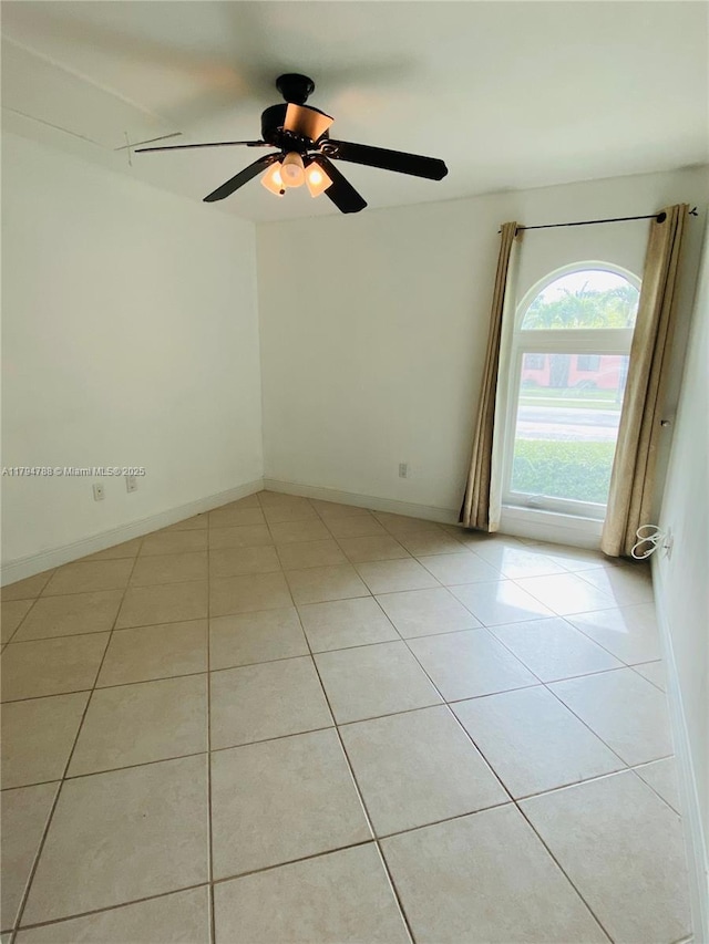 empty room featuring baseboards, a ceiling fan, and light tile patterned flooring