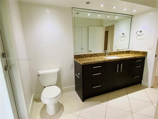 bathroom with baseboards, tile patterned flooring, toilet, and vanity