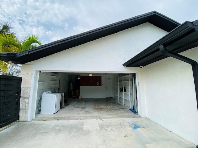 exterior space featuring washer and dryer, stucco siding, and driveway