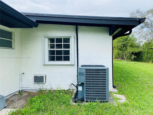 view of property exterior with a lawn, central AC unit, and stucco siding