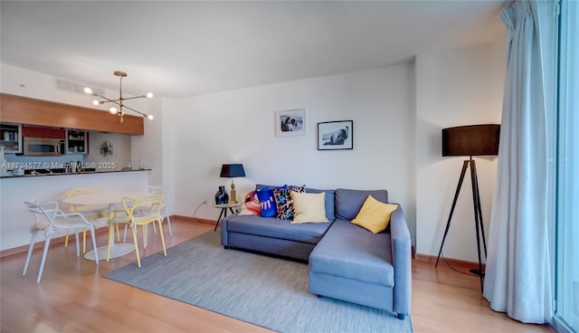 living room with baseboards, a notable chandelier, and light wood-type flooring
