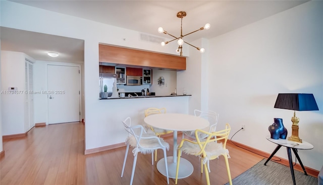dining area featuring baseboards, a notable chandelier, and wood finished floors