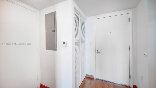 corridor with electric panel and light wood-type flooring