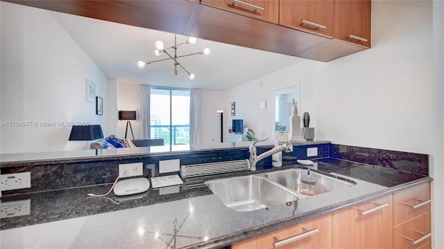 kitchen featuring a sink, dark stone countertops, open floor plan, and a notable chandelier