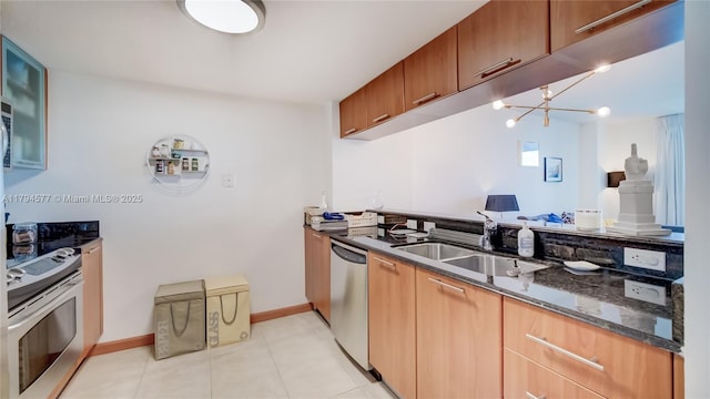kitchen with a sink, a chandelier, dark stone countertops, stainless steel appliances, and light tile patterned floors