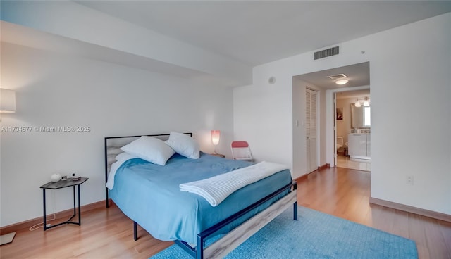 bedroom with baseboards, a closet, wood finished floors, and visible vents