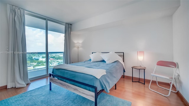 bedroom with baseboards, wood finished floors, and expansive windows