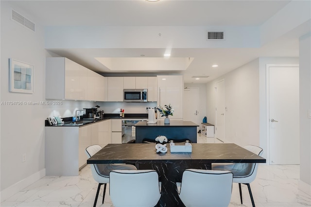 kitchen featuring modern cabinets, stainless steel microwave, and visible vents