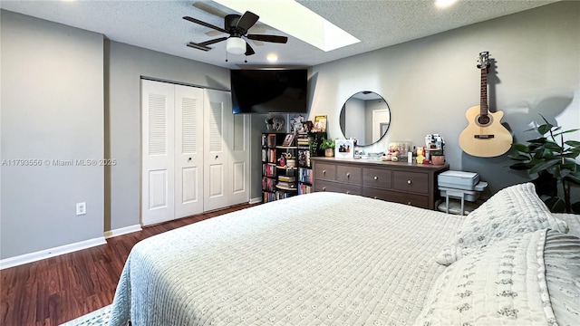 bedroom featuring a skylight, wood finished floors, baseboards, a closet, and recessed lighting