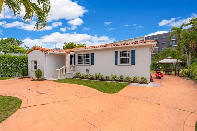 mediterranean / spanish-style home with a gazebo, a patio area, stucco siding, and a tile roof
