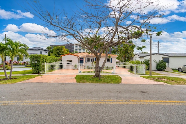 bungalow-style home with concrete driveway, a tile roof, a gate, and stucco siding