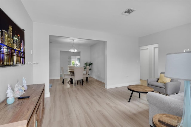 living area featuring a chandelier, baseboards, visible vents, and light wood-type flooring