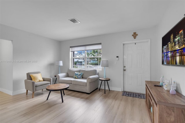 living area with light wood-style floors, baseboards, and visible vents
