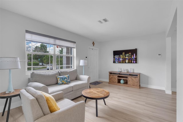 living room with baseboards, light wood finished floors, and visible vents