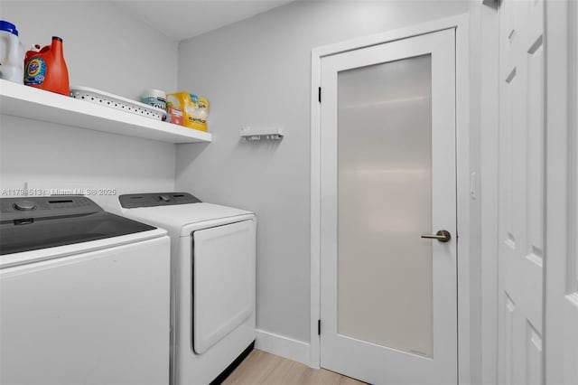 clothes washing area featuring laundry area, light wood finished floors, independent washer and dryer, and baseboards