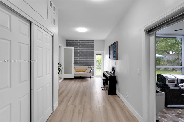 hallway featuring visible vents, plenty of natural light, and light wood-style flooring