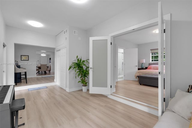 corridor featuring baseboards, visible vents, and light wood-type flooring