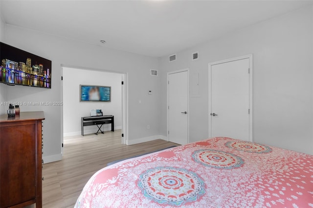 bedroom featuring visible vents, light wood-style flooring, and baseboards