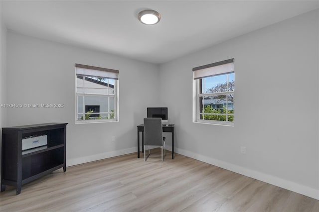 office area featuring a healthy amount of sunlight, baseboards, and wood finished floors