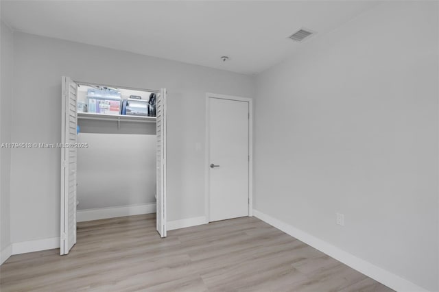 unfurnished bedroom featuring visible vents, baseboards, wood finished floors, and a closet
