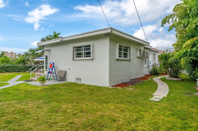 rear view of house featuring a patio area, stucco siding, a yard, and a wall mounted air conditioner