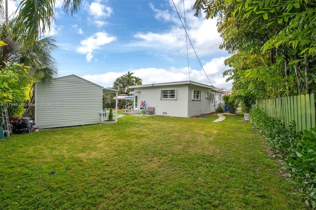 rear view of property with stucco siding, fence, and a yard
