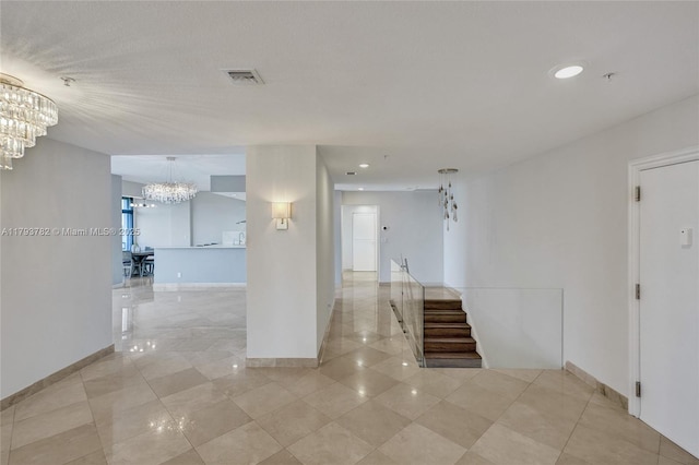 corridor with an inviting chandelier, baseboards, light tile patterned flooring, and visible vents