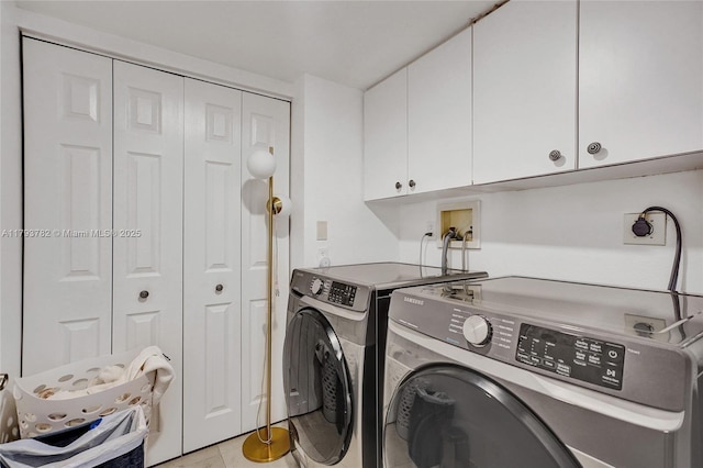 clothes washing area featuring washer and clothes dryer, cabinet space, and light tile patterned flooring