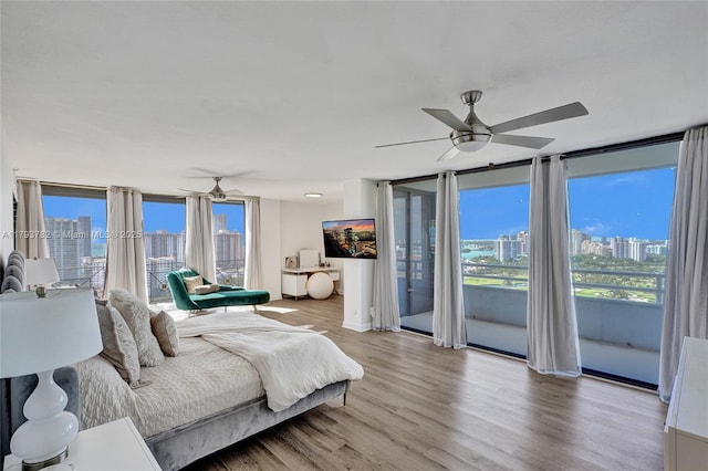 bedroom featuring access to outside, a ceiling fan, wood finished floors, and multiple windows