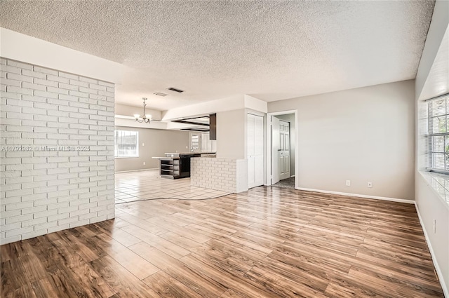 4109 NW 79th Ave, Coral Springs, FL 33065 - unfurnished living room featuring a healthy amount of sunlight, a textured ceiling, wood finished floors, and a notable chandelier