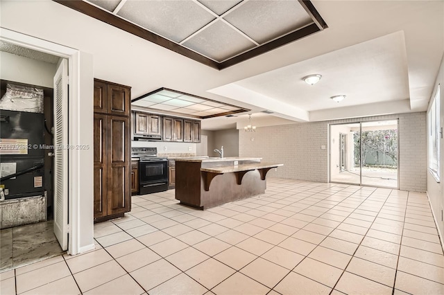 4109 NW 79th Ave, Coral Springs, FL 33065 - kitchen with light countertops, brick wall, a kitchen bar, a tray ceiling, and black range with electric cooktop