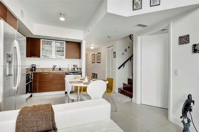 kitchen featuring a sink, light tile patterned floors, stainless steel refrigerator with ice dispenser, visible vents, and modern cabinets