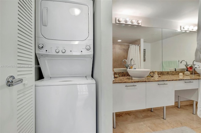 clothes washing area featuring stacked washing maching and dryer, laundry area, and a sink