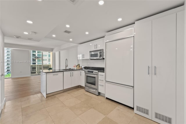 kitchen with visible vents, dark countertops, a sink, a peninsula, and stainless steel appliances