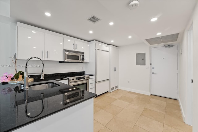 kitchen with a sink, white cabinets, dark stone countertops, stainless steel appliances, and recessed lighting