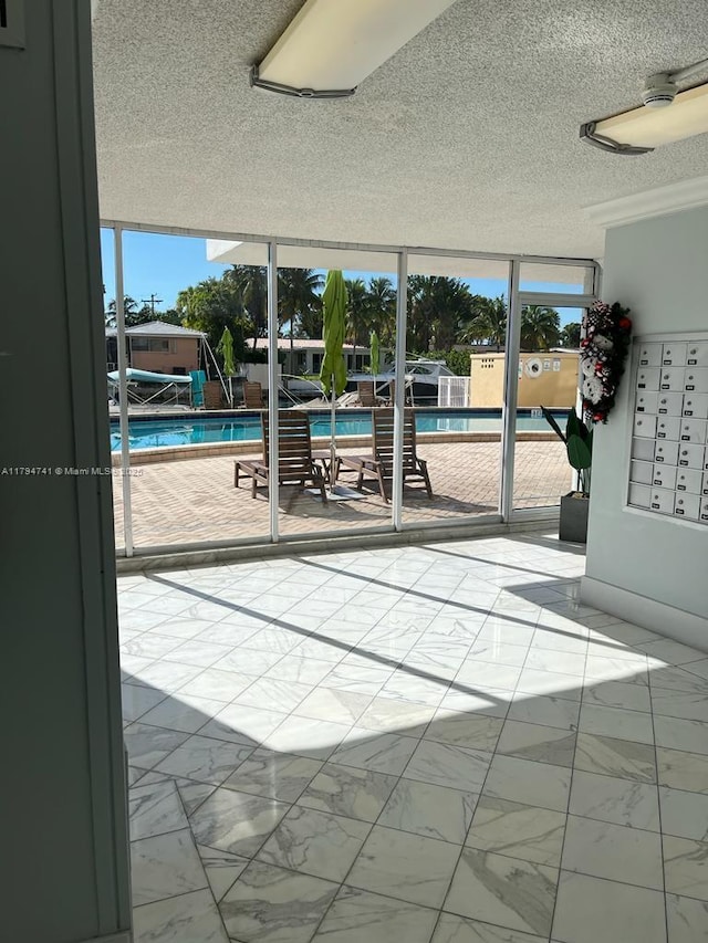 doorway to outside with a textured ceiling and marble finish floor