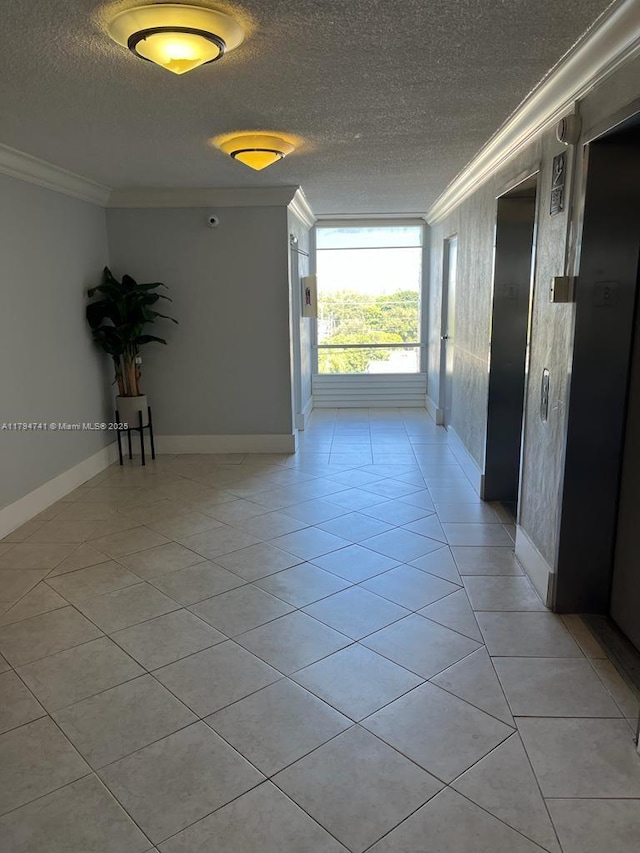 hall with crown molding, a textured ceiling, baseboards, and light tile patterned flooring
