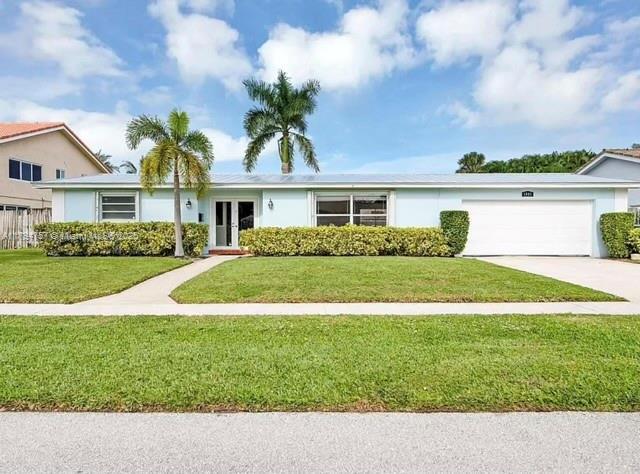 ranch-style home with an attached garage, stucco siding, driveway, and a front yard