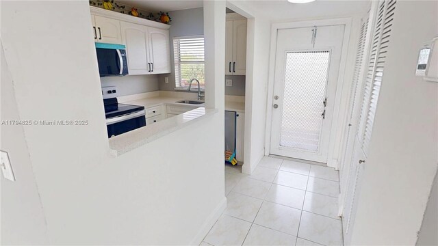 9900 Sunrise Lakes Blvd Unit 309, Sunrise, FL 33322 - kitchen with stainless steel range with electric cooktop, a sink, light countertops, white cabinets, and light tile patterned floors
