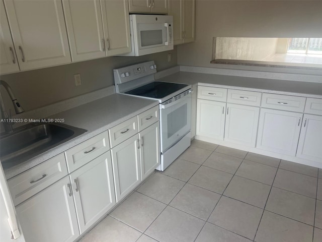 kitchen featuring a sink, light tile patterned floors, white cabinets, light countertops, and white appliances