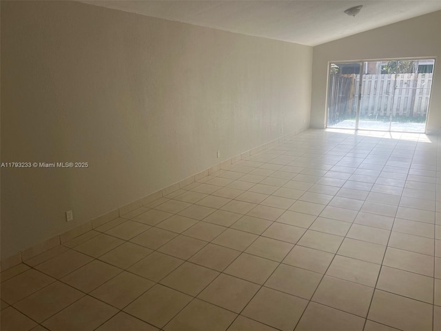 empty room featuring vaulted ceiling and light tile patterned floors