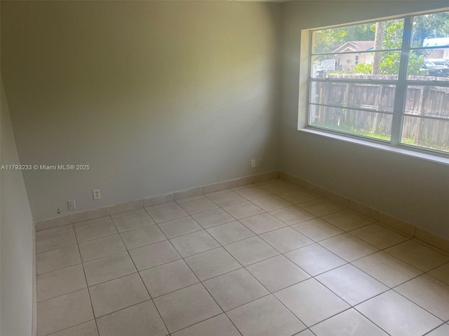 spare room with baseboards, plenty of natural light, and light tile patterned floors
